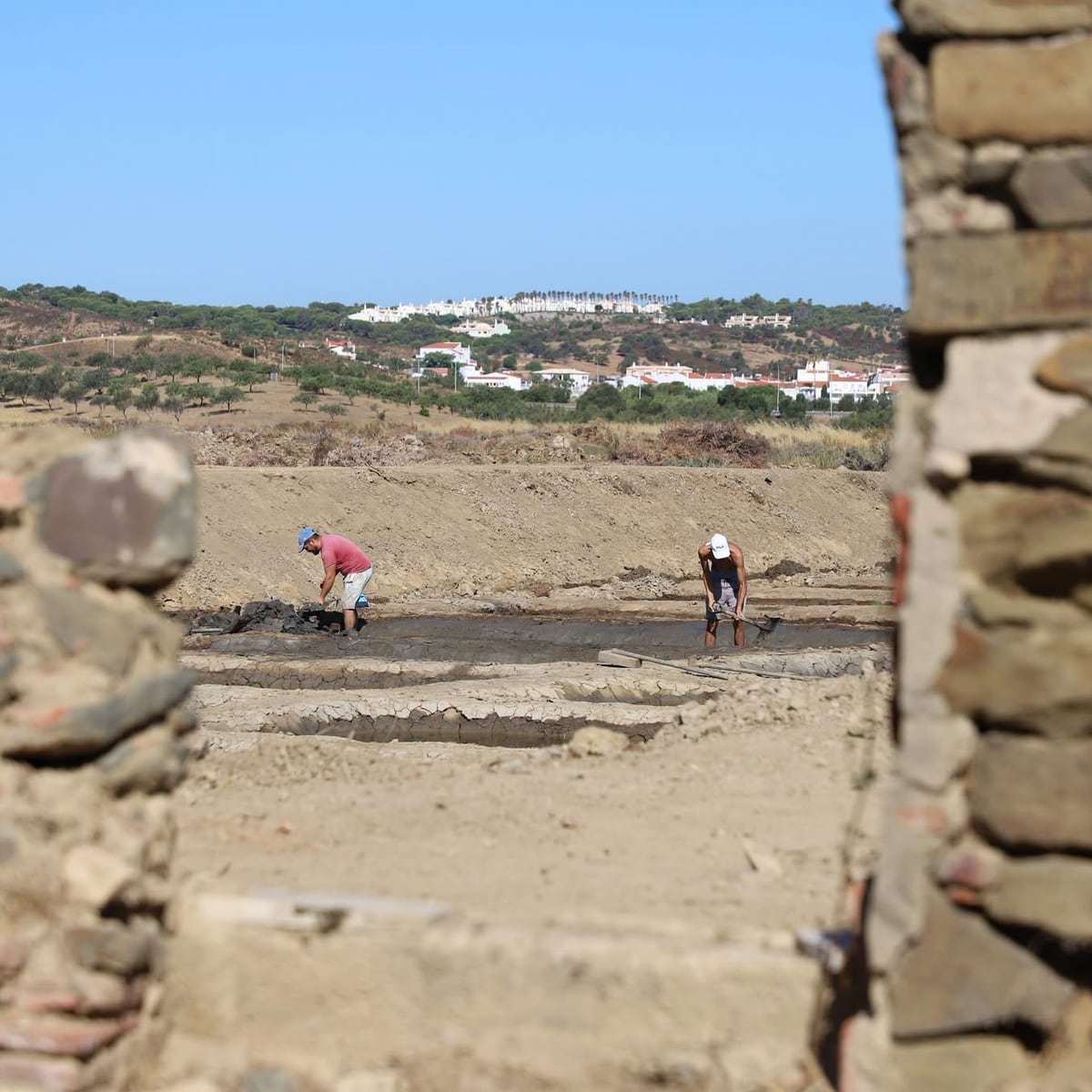 The salt pans seen through the wall of the old warehouse being rehabilitated.